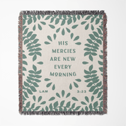 Blanket with green leaf pattern and text 'His mercies are new every morning' on a white background
