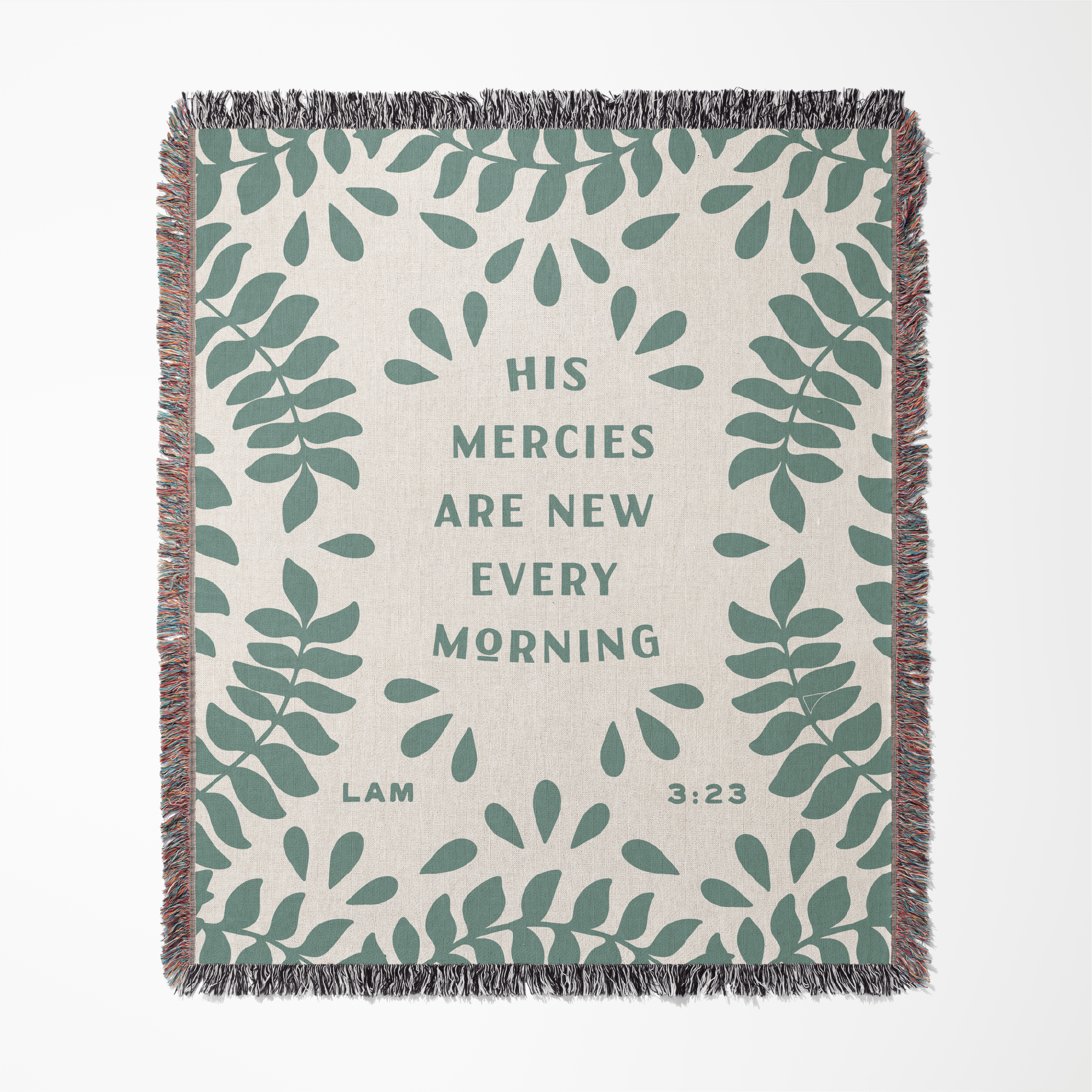 Blanket with green leaf pattern and text 'His mercies are new every morning' on a white background