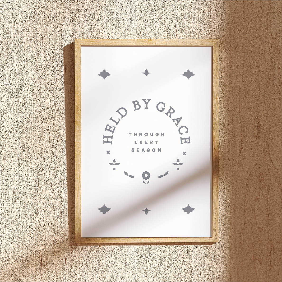 Framed print with 'Held by Grace' text on a wooden wall.