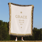 Blanket with 'GRACE NEVER FAILS ME' text in a natural setting