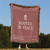 Blanket with 'Rooted in Peace' text and design, displayed outdoors.