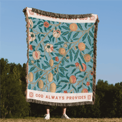 Decorative blanket with floral pattern and 'God Always Provides' text, held by a person outdoors.