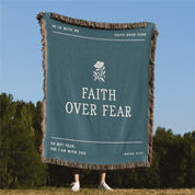 Green blanket with 'Faith Over Fear' text and design, held up outdoors.