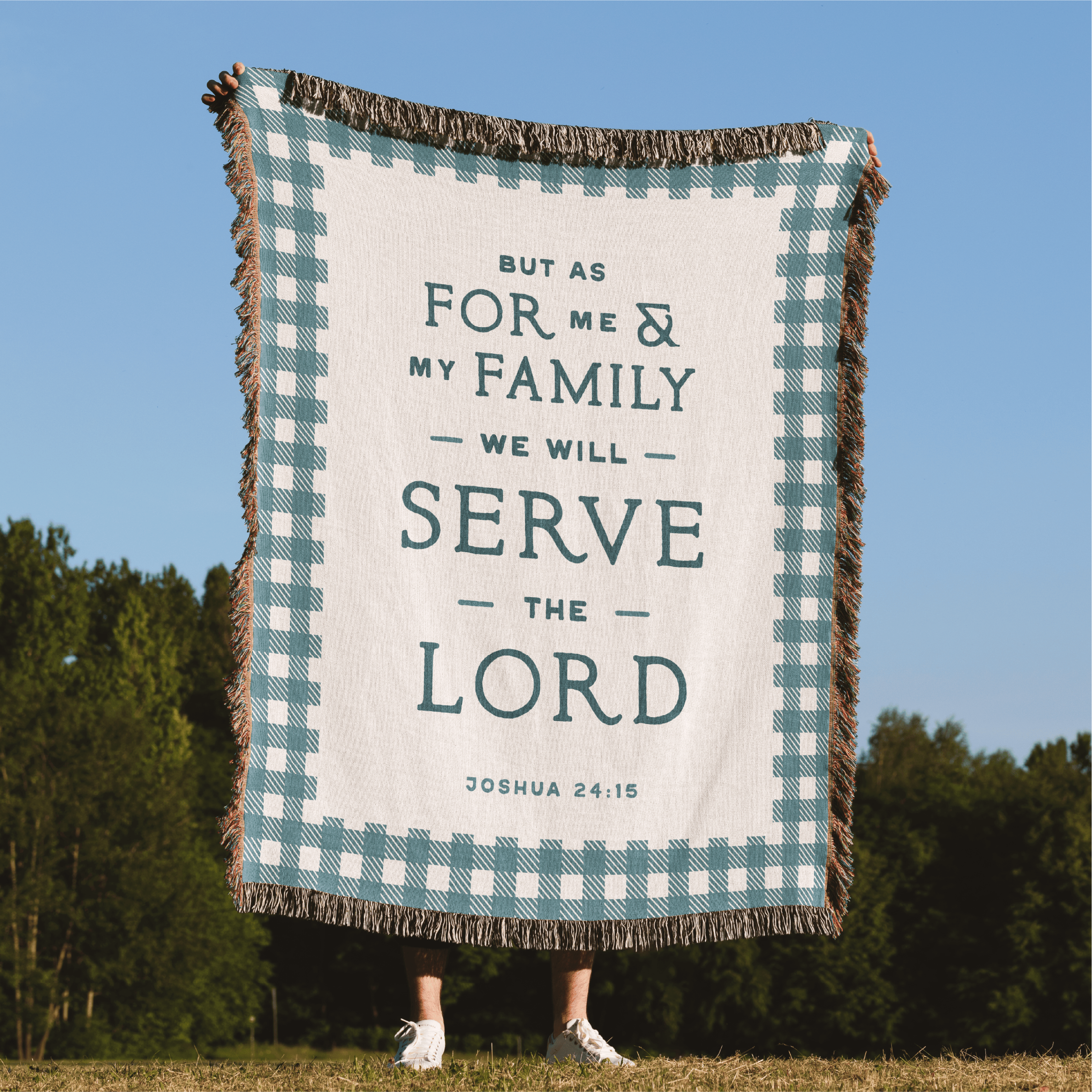 Blanket with text 'But as for me and my family, we will serve the Lord' by Joshua 24:15, held by a person outdoors.