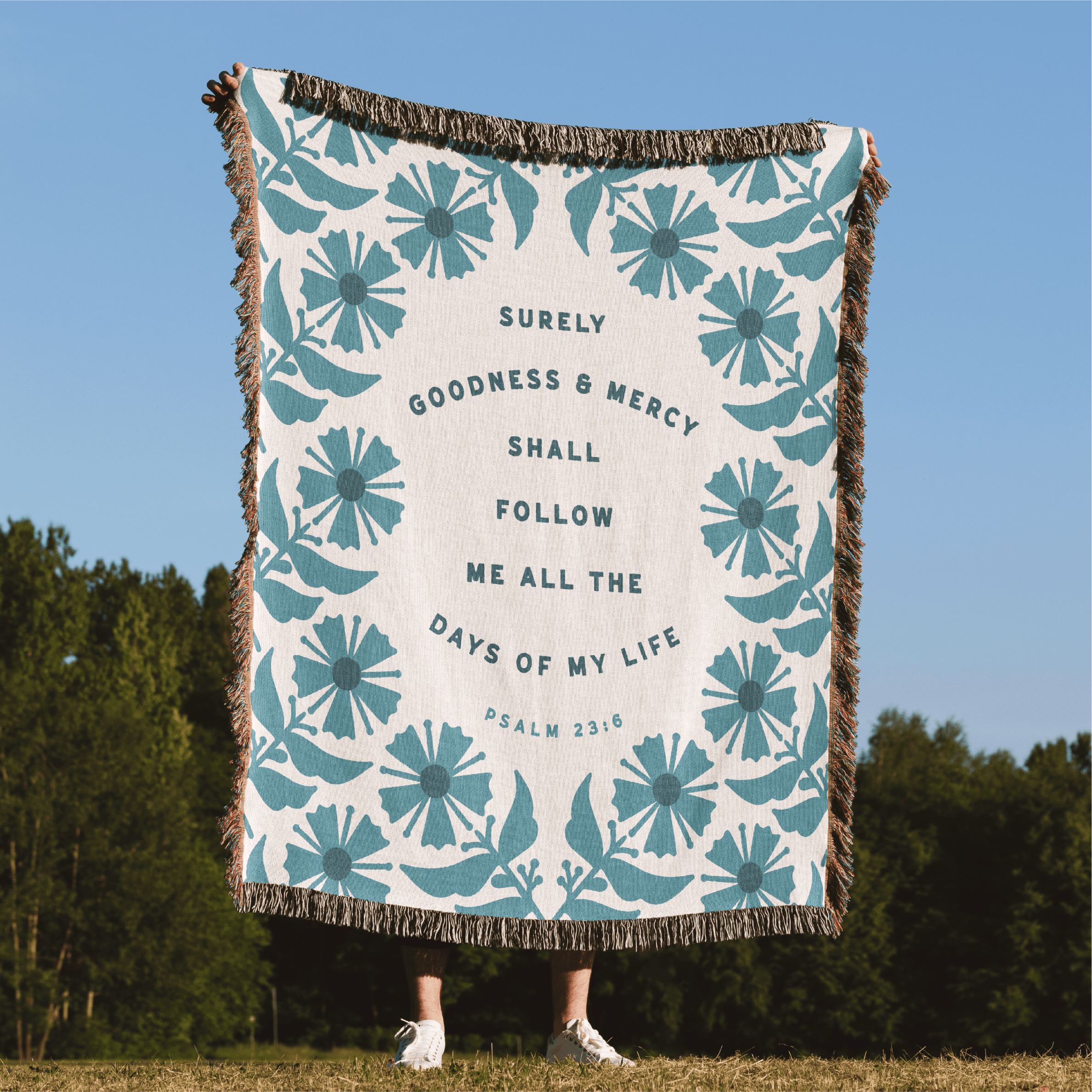 Floral patterned blanket with text on a grassy field