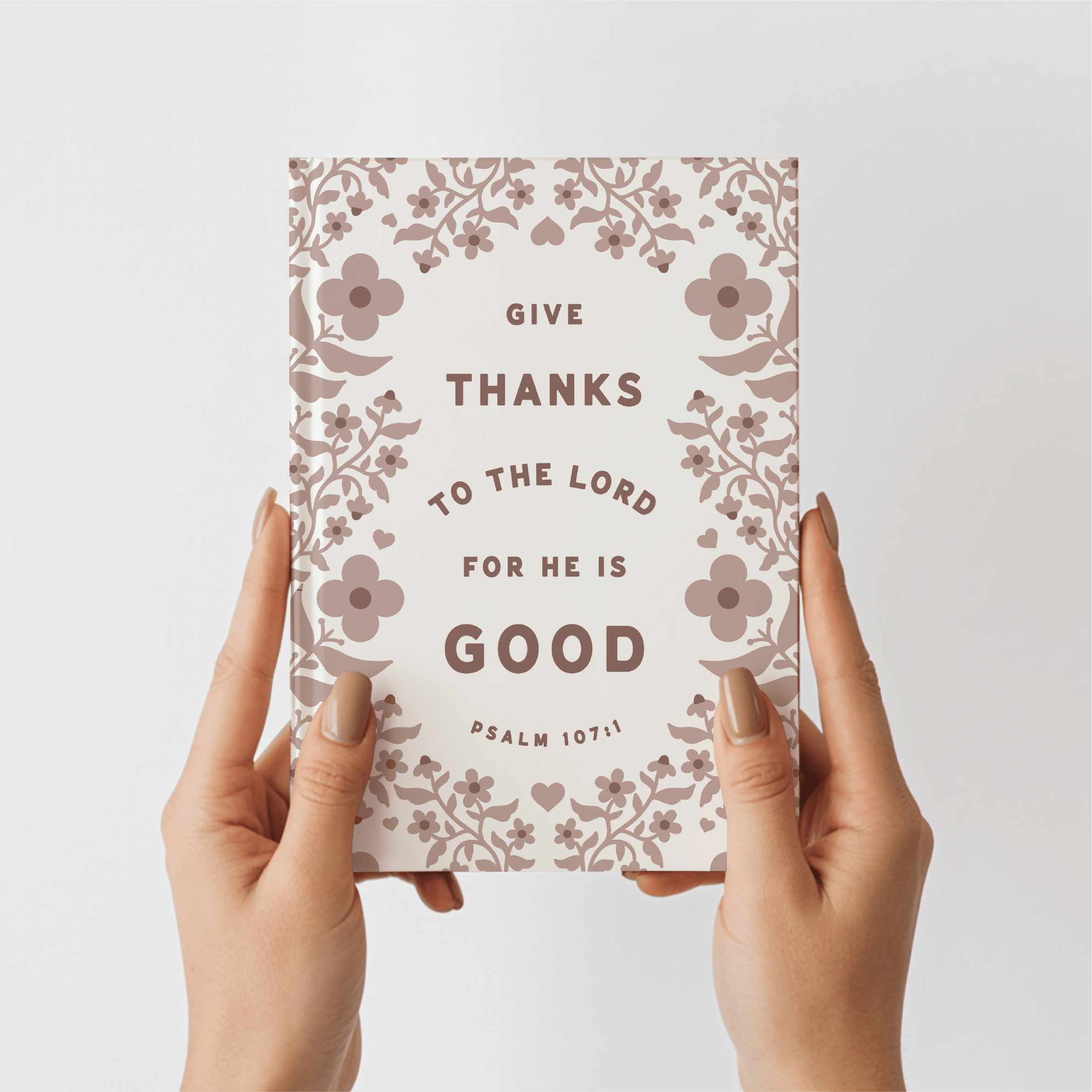 Card with floral design and text held by hands against a light background