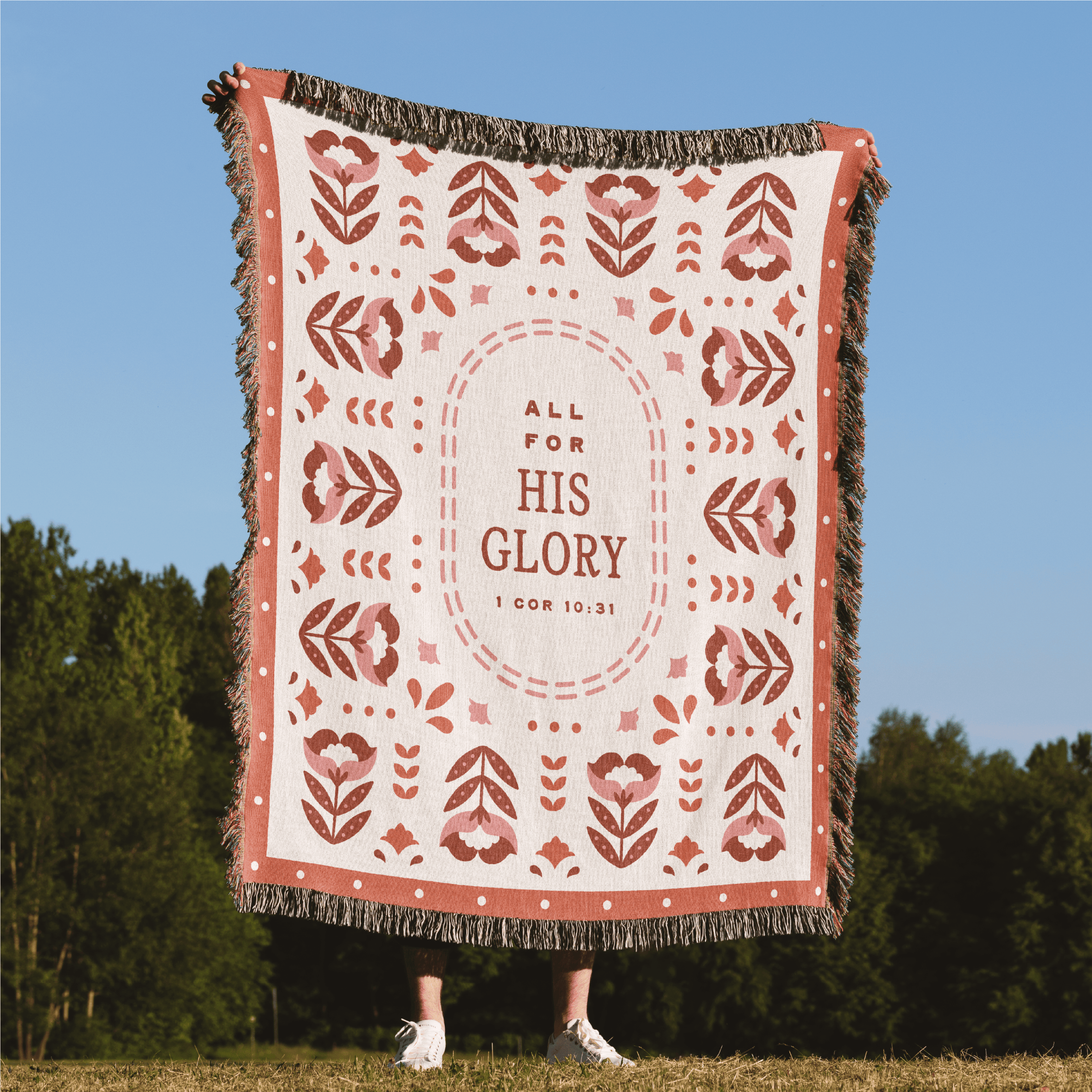 Decorative blanket with 'All for His Glory' text in a natural setting