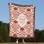 Decorative blanket with floral pattern and text in a natural setting