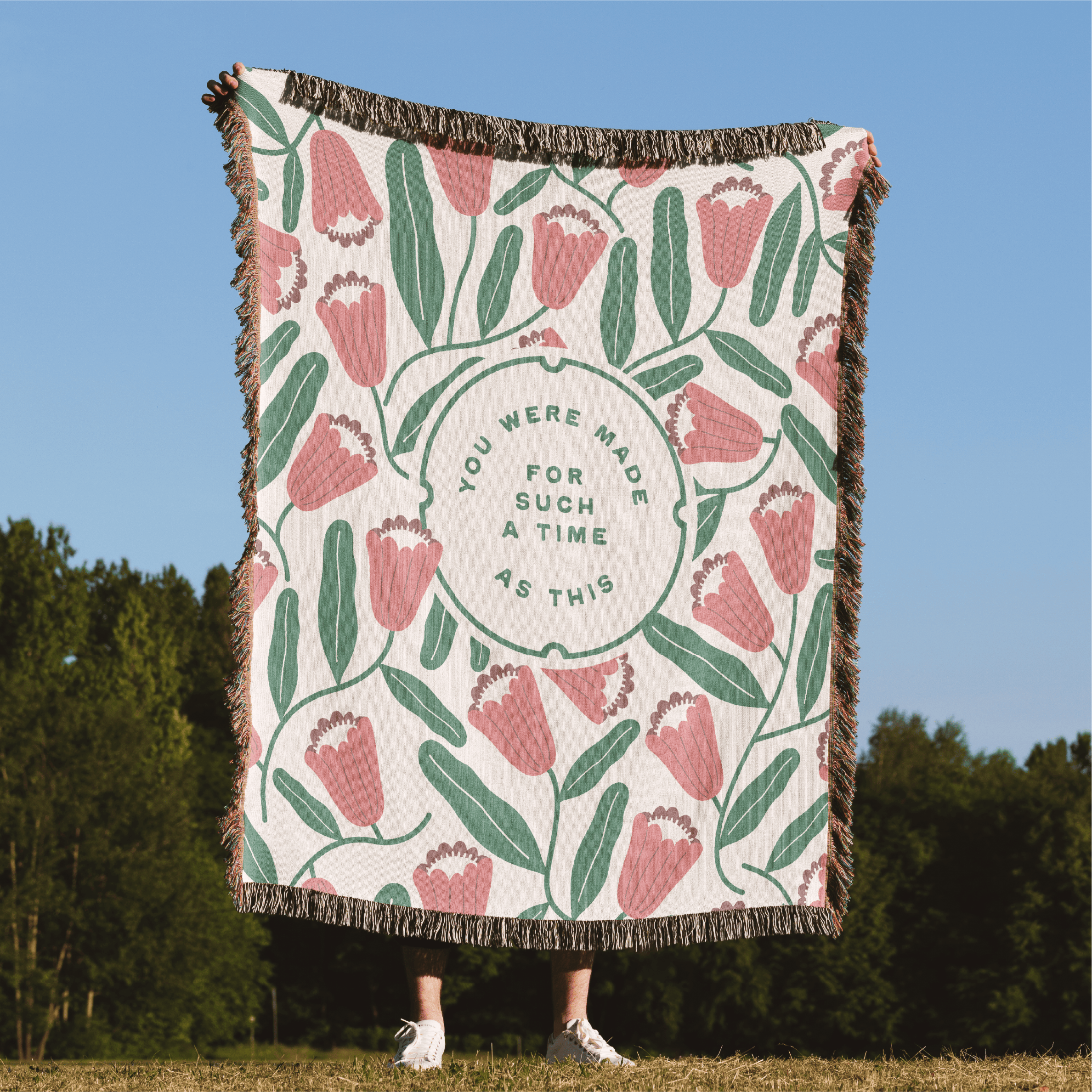 Floral patterned blanket with text on a grassy field