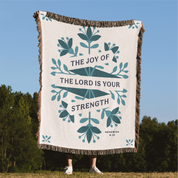 Blanket with 'The Joy of the Lord is Your Strength' text and floral design outdoors
