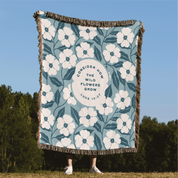 Floral patterned blanket with text on a grassy field