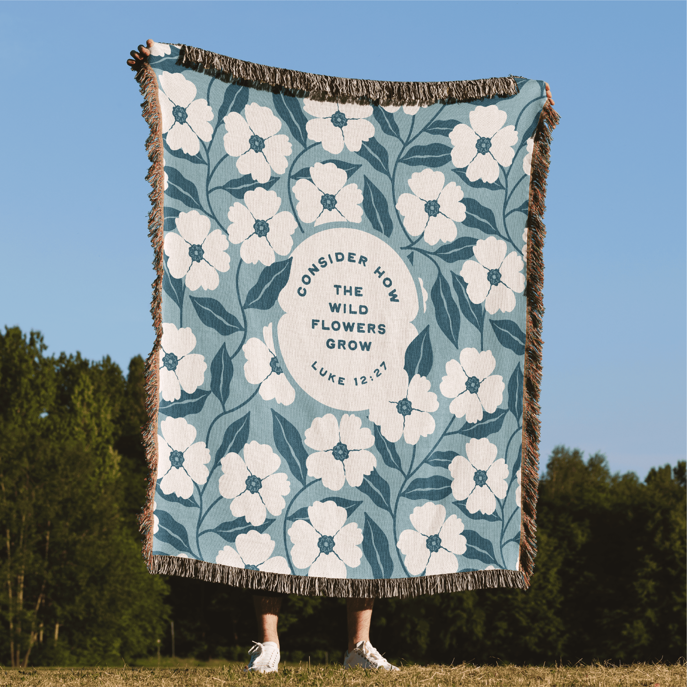 Floral patterned blanket with text on a grassy field