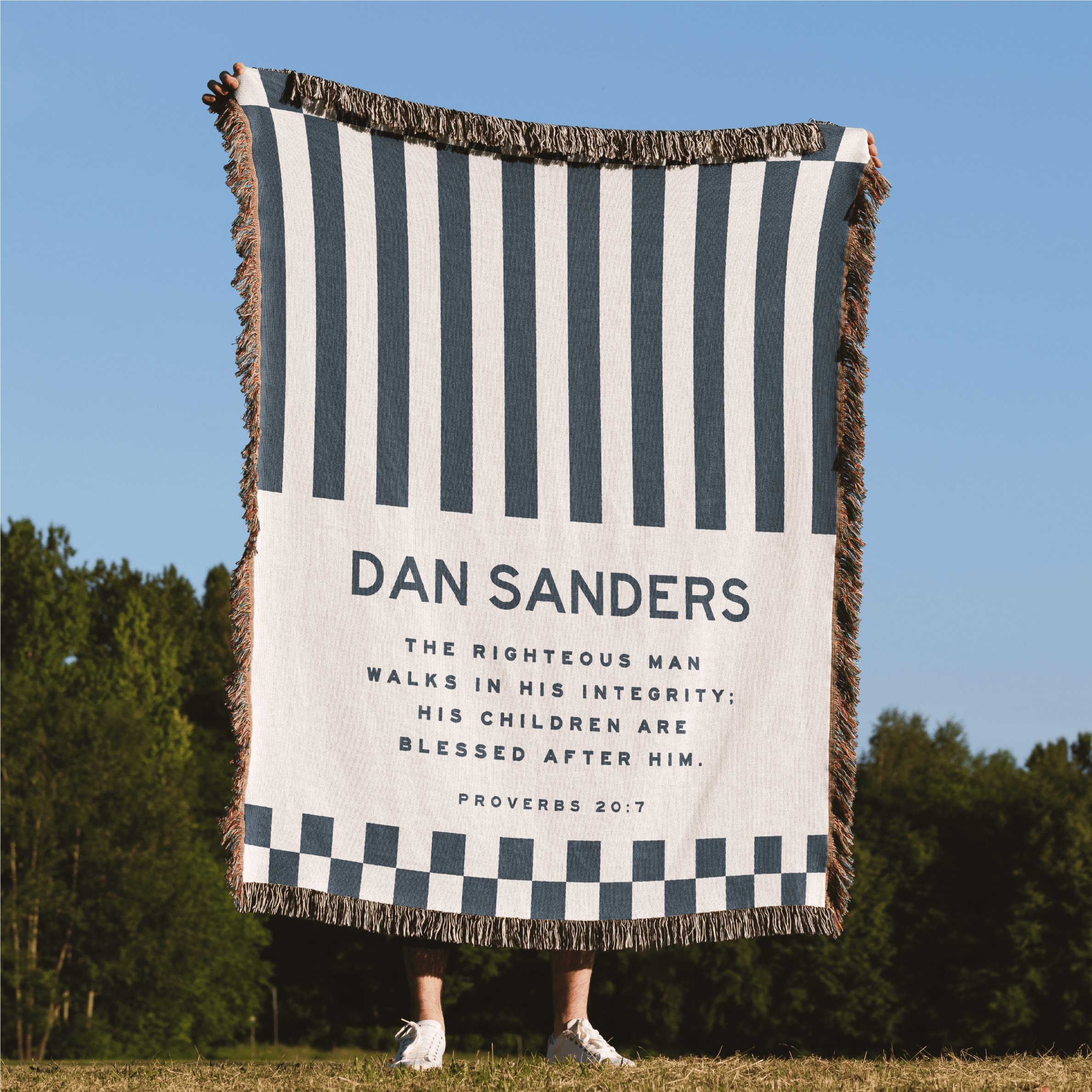 Striped blanket with text and graphics on a grassy field