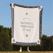 Blanket with 'Faithful Through It All' text in a natural setting