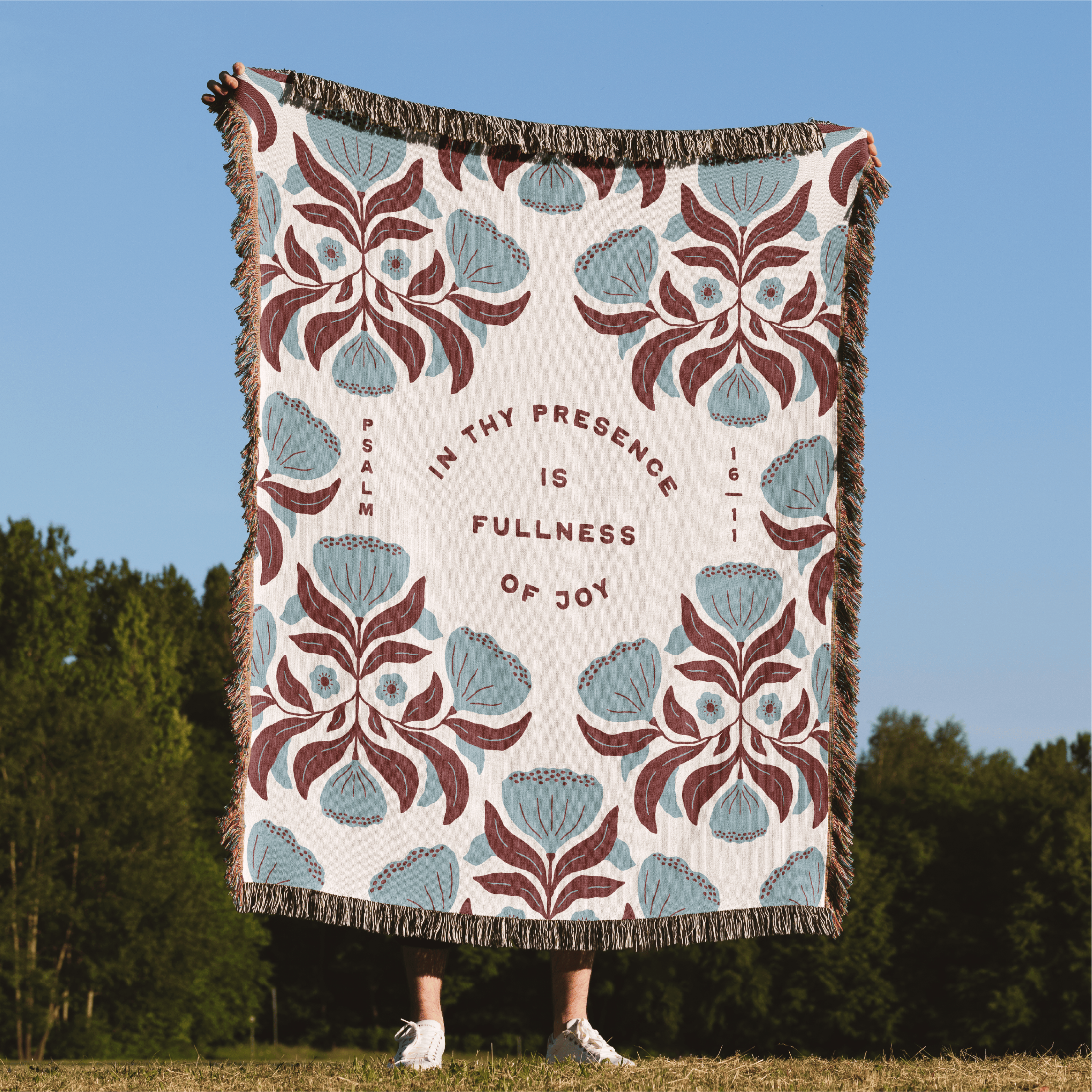 Decorative blanket with floral pattern and text in a natural setting