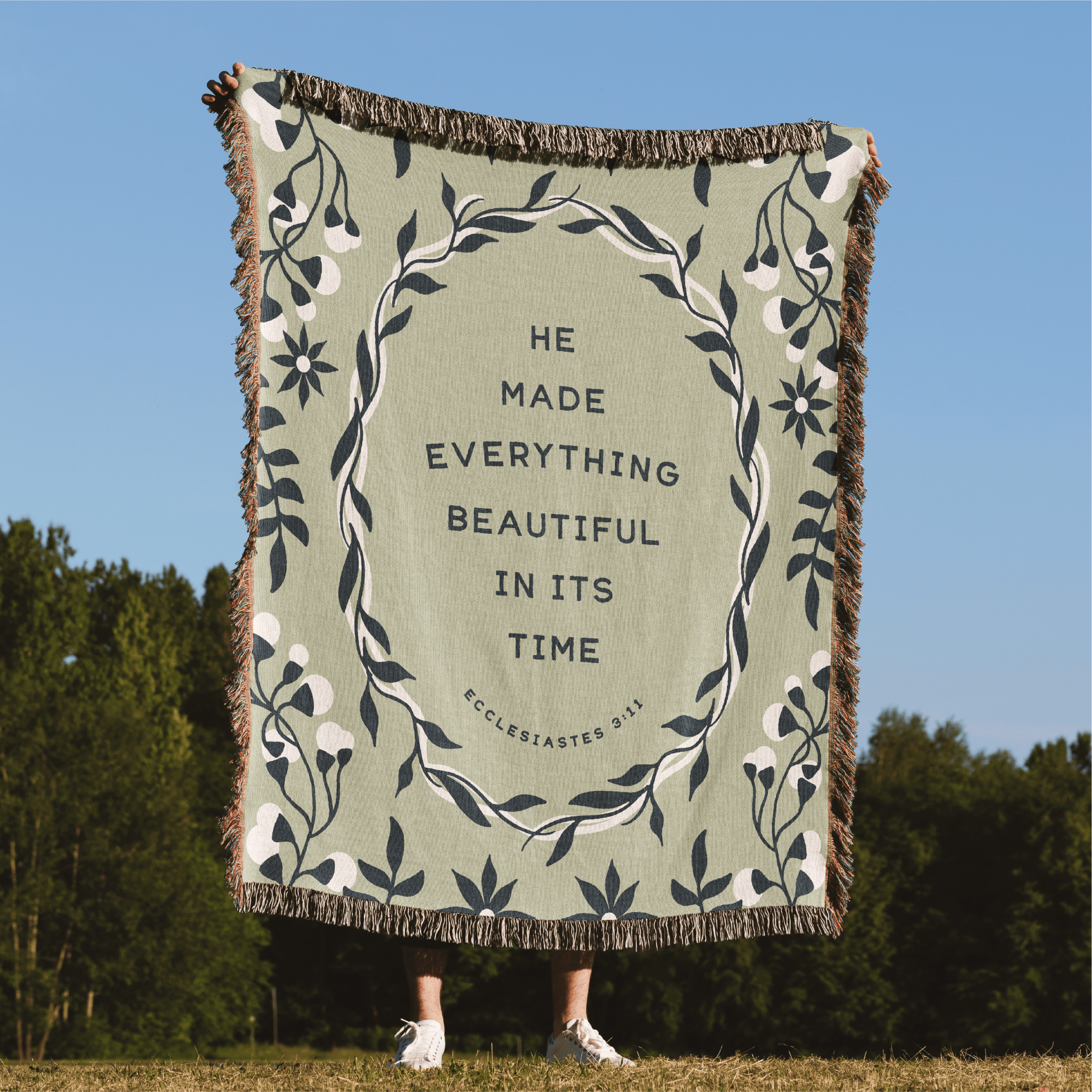 Blanket with text and floral design in a natural setting