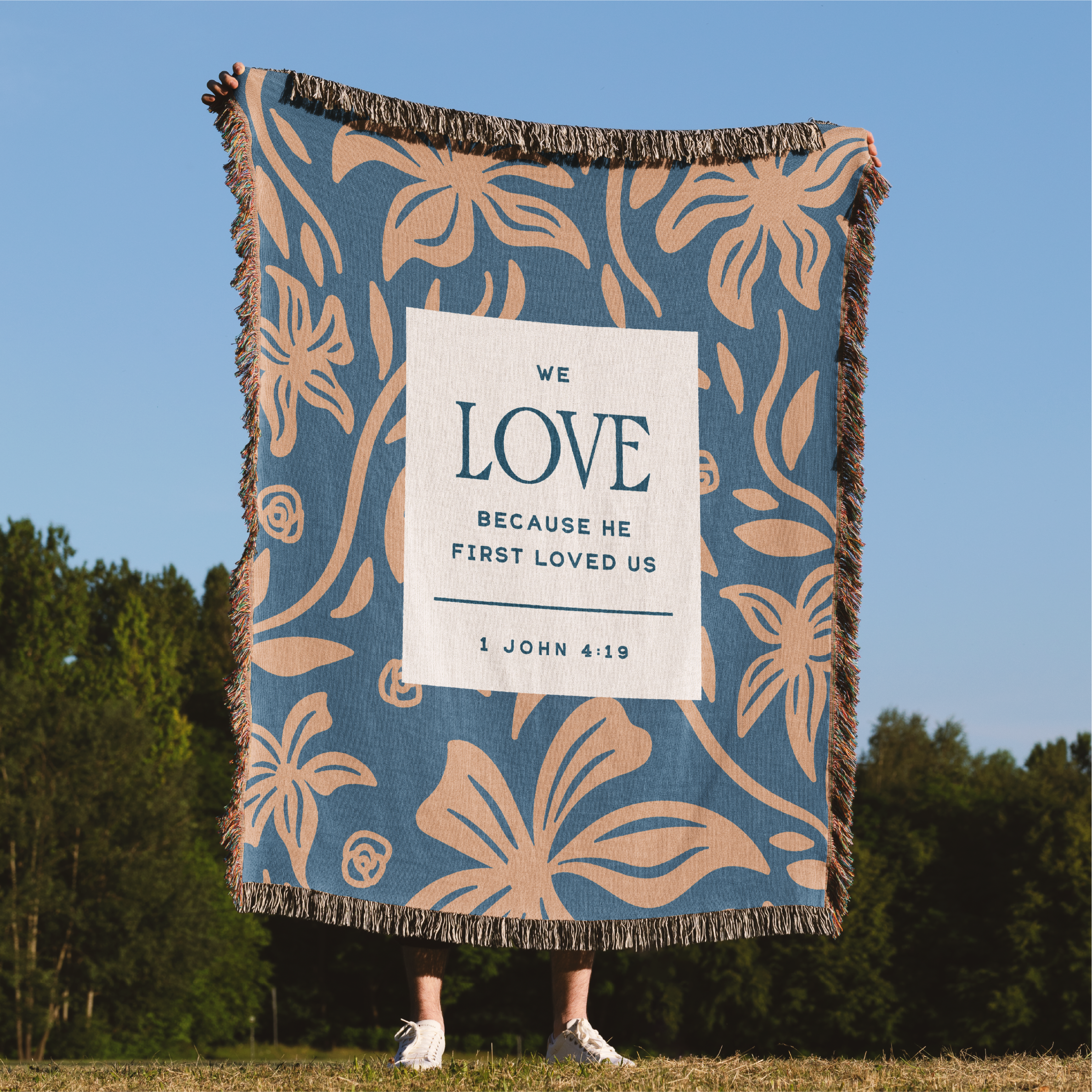 Floral-patterned blanket with a text card held by a person outdoors