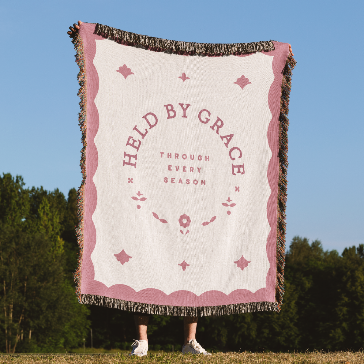 Blanket with 'Held by Grace' text in a scenic outdoor setting