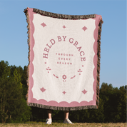 Blanket with 'Held by Grace' text in a scenic outdoor setting