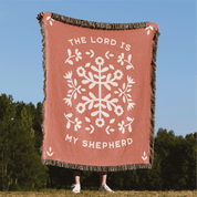 Blanket with floral design and 'The Lord is my Shepherd' text in a natural setting