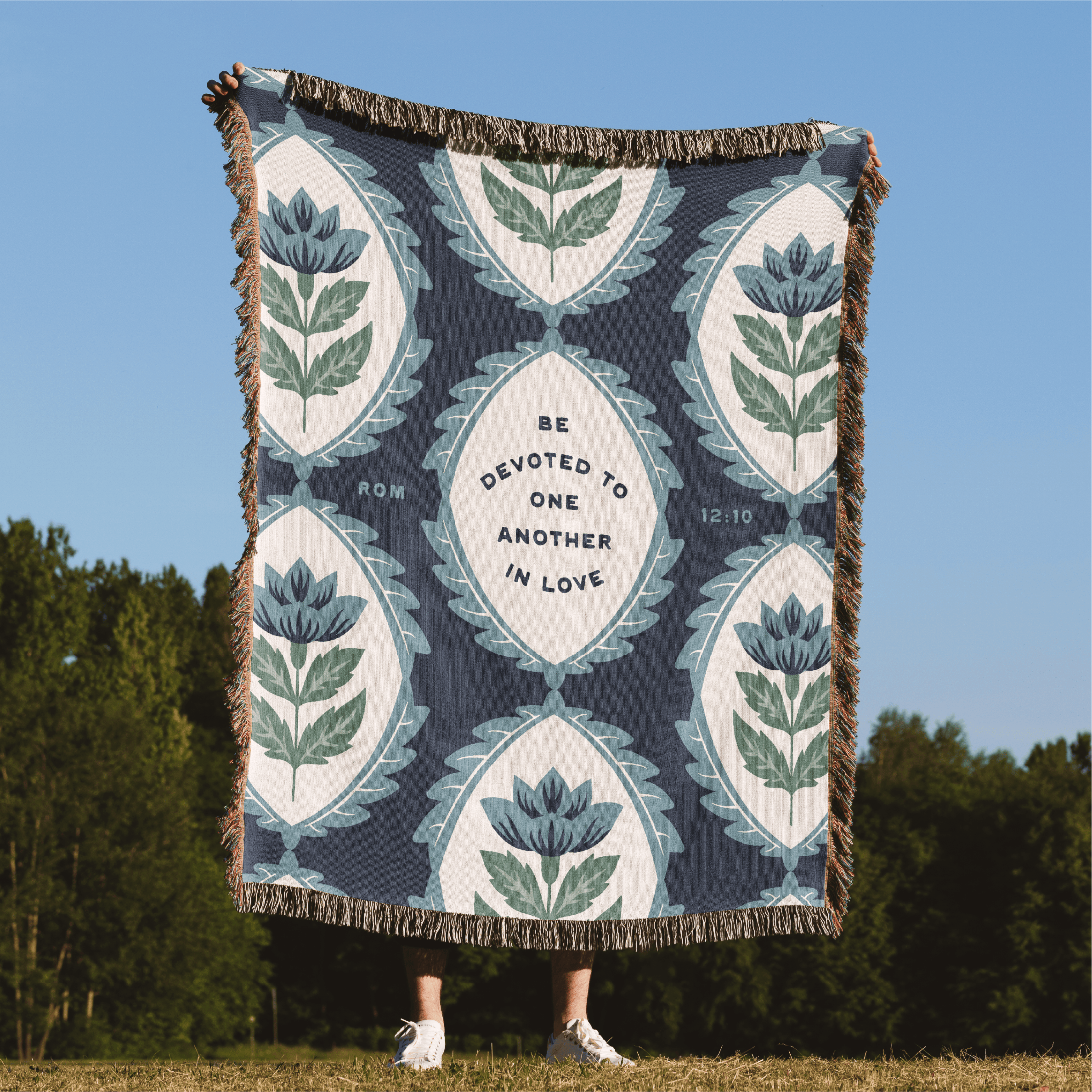 Floral patterned throw blanket with text on a grassy field