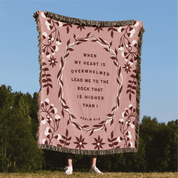 Pink blanket with floral design and text against a blue sky and green trees background