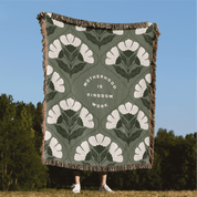 Floral patterned throw blanket with text on a grassy field with trees in the background