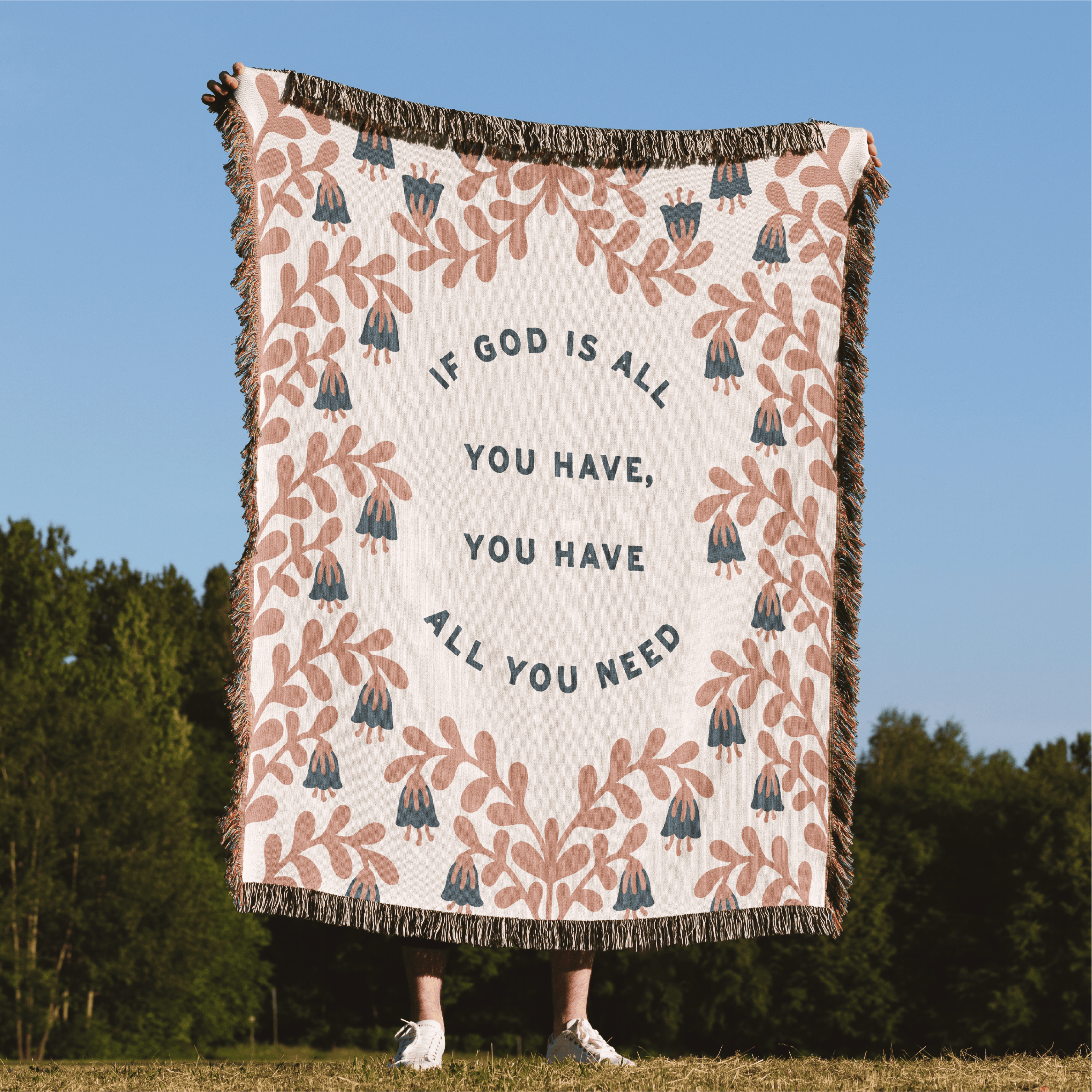 Blanket with motivational quote and floral patterns in a natural setting