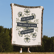 Blanket with 'The Joy of the Lord is Your Strength' text and floral design outdoors