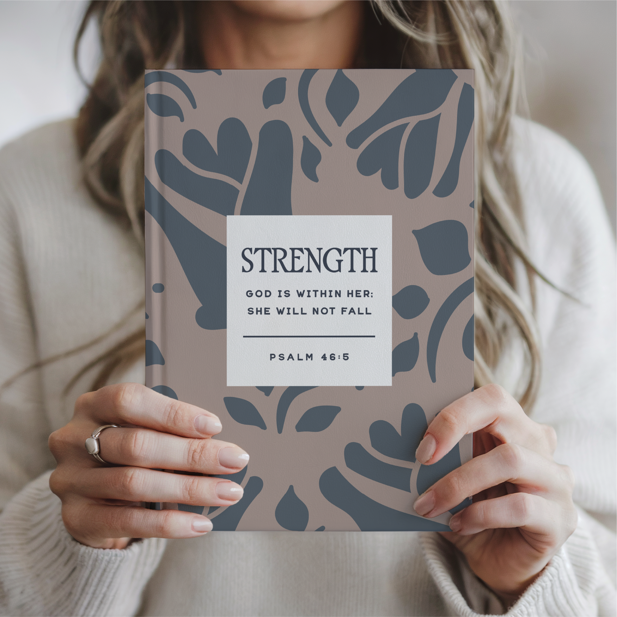 Person holding a book with a decorative cover and motivational quote