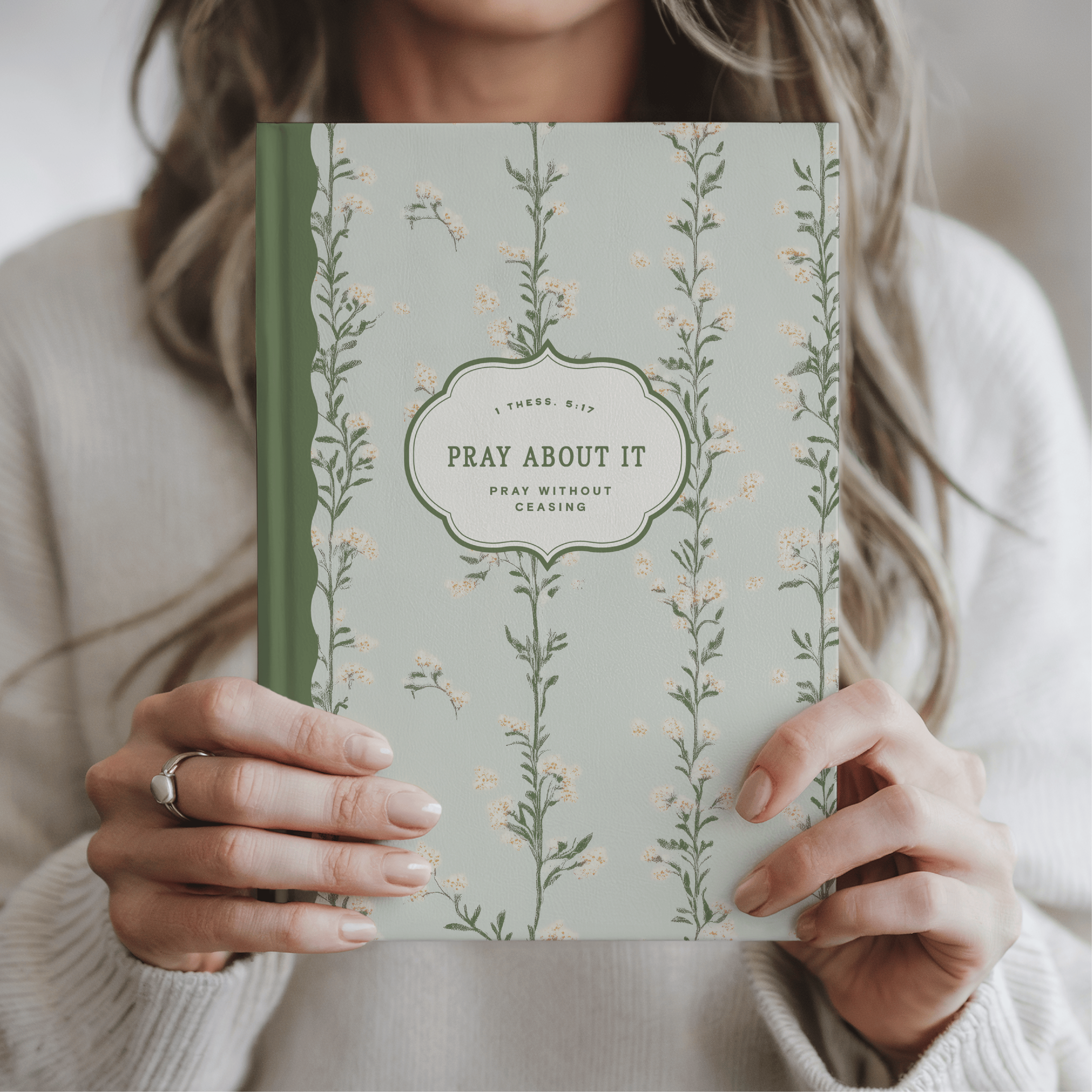 Person holding a book titled 'Pray About It' with floral design