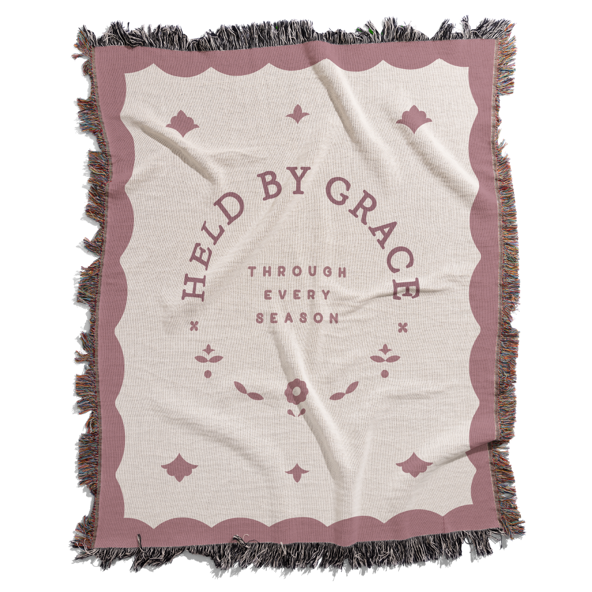 Blanket with 'Held by Grace' text and decorative border on a white background