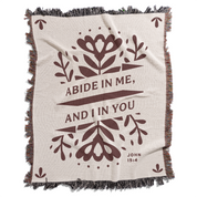 Blanket with floral design and text 'Abide in me, and I in you' on a white background
