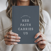 Person holding a book titled 'Her Faith Carries Us' by Timothy 1:8.