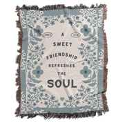 Floral patterned blanket with text 'A sweet friendship refreshes the soul' on a white background