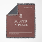 Blanket with 'Rooted in Peace' text and floral design on a white background
