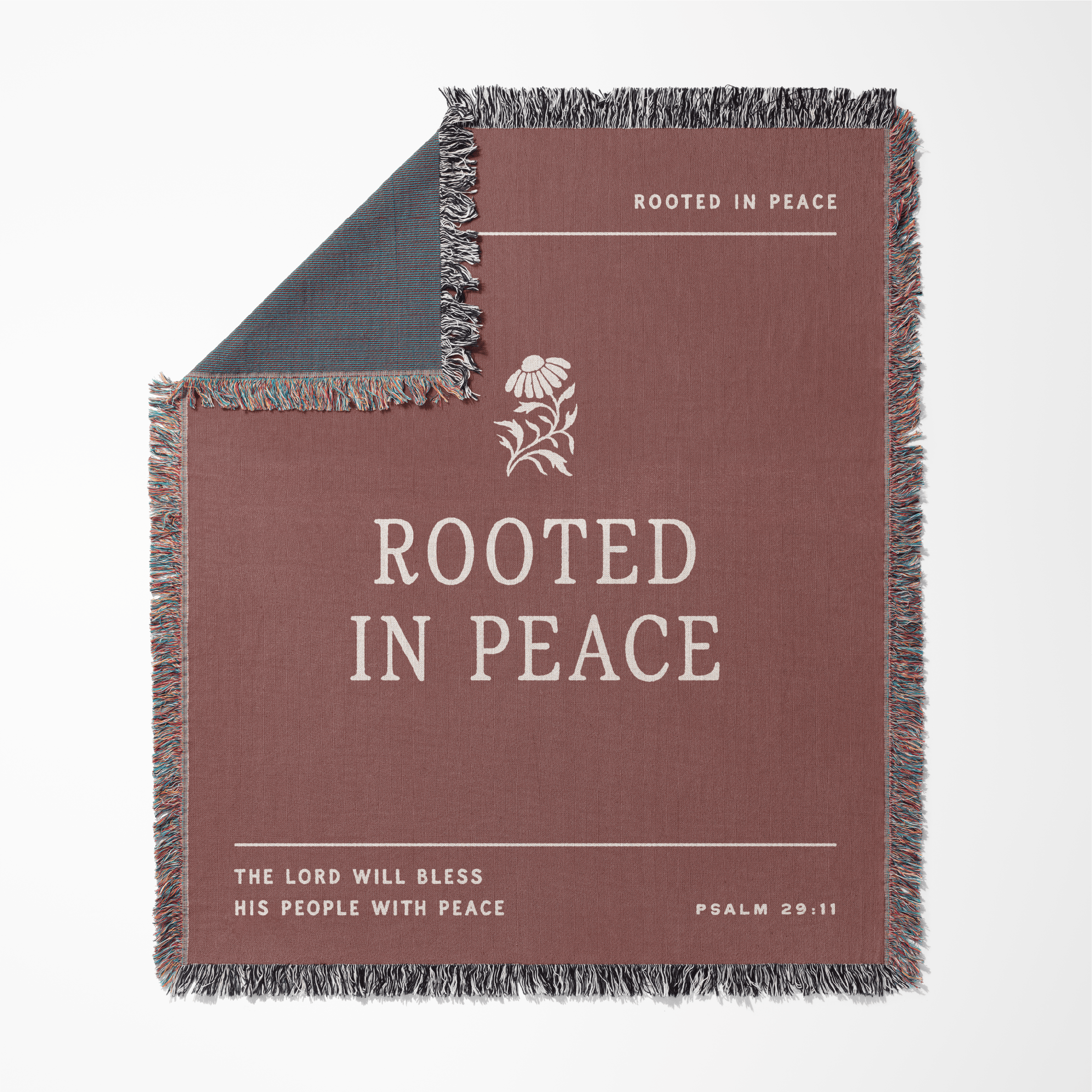 Blanket with 'Rooted in Peace' text and floral design on a white background