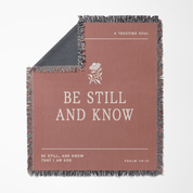 Blanket with 'Be Still and Know' text and design on a white background