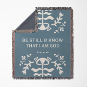 Blue blanket with white floral patterns and text 'Be Still & Know That I Am God' on a white background