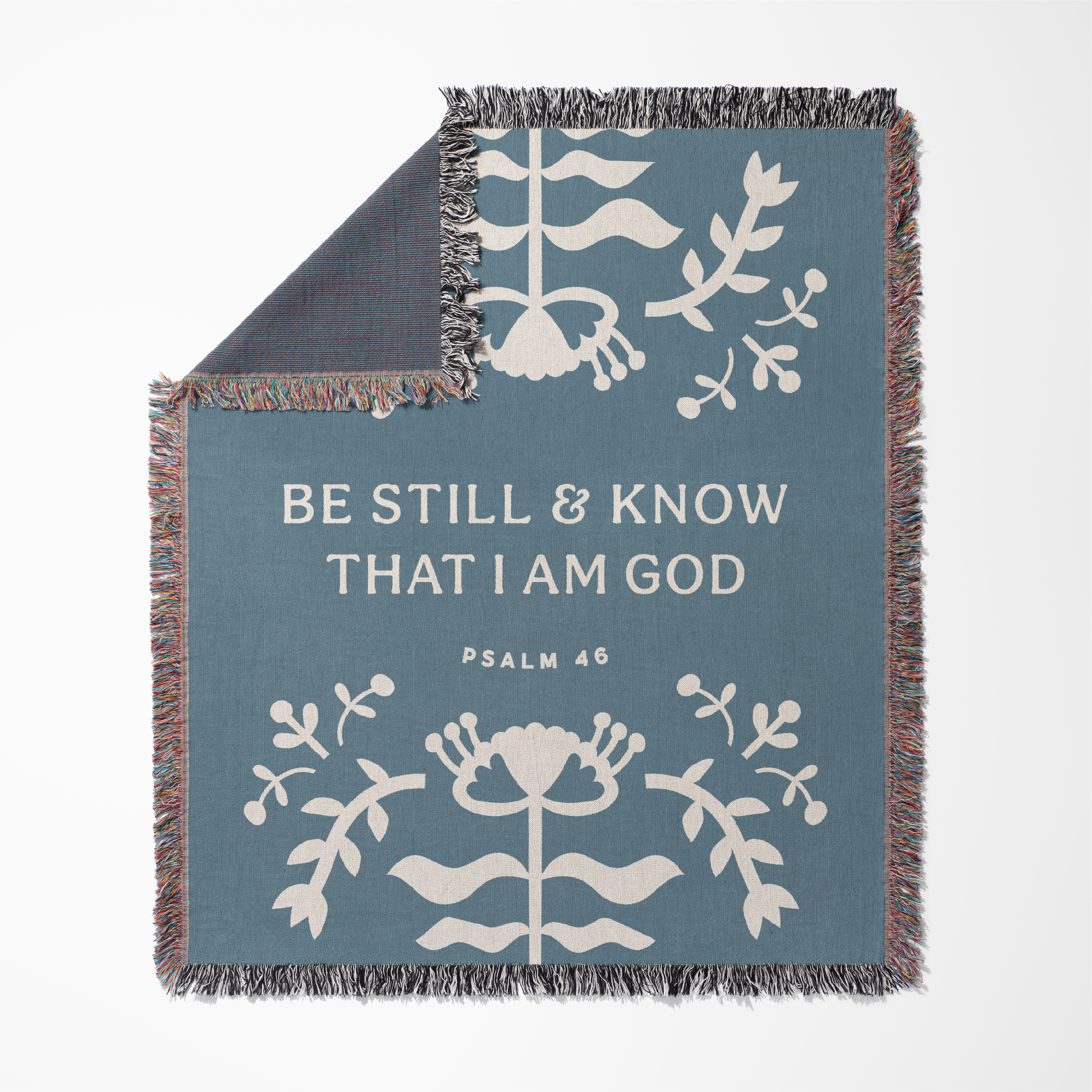Blue blanket with white floral patterns and text 'Be Still & Know That I Am God' on a white background