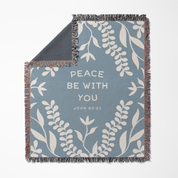 Decorative blanket with leaf pattern and 'Peace Be With You' text on a blue background