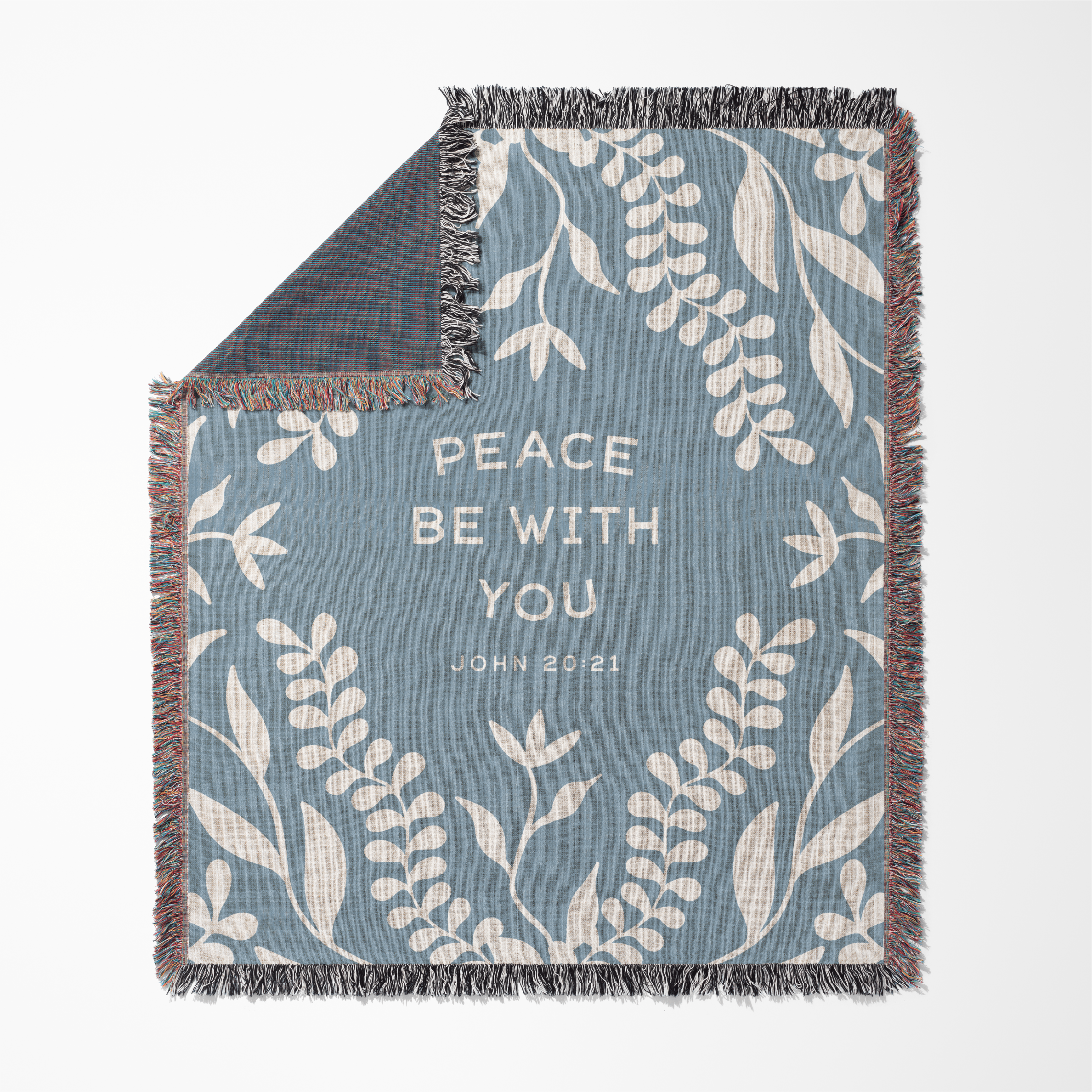 Decorative blanket with leaf pattern and 'Peace Be With You' text on a blue background