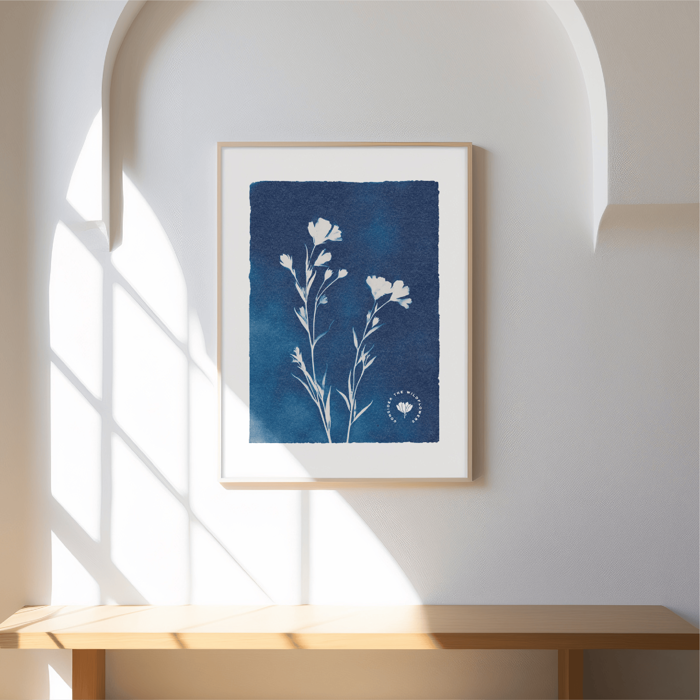 Framed artwork with a blue square and white floral design on a white wall.