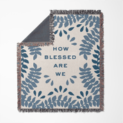 Blanket with blue leaf pattern and 'How Blessed Are We' text on a white background