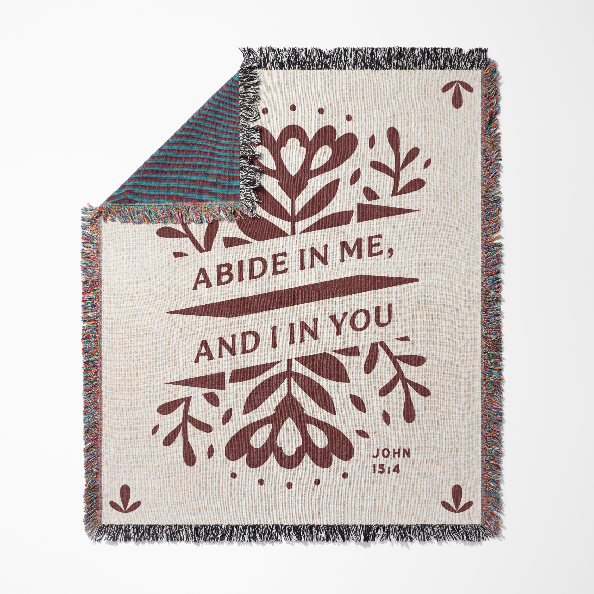 Blanket with floral design and text 'Abide in me, and I in you' from John 15:4 on a white background