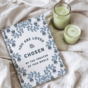 Notebook with motivational quote on a bed with two candles