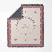 Blanket with 'Help by Grace through every season' text on a white background