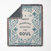 Floral-patterned blanket with text 'A sweet friendship refreshes the soul' on a white background