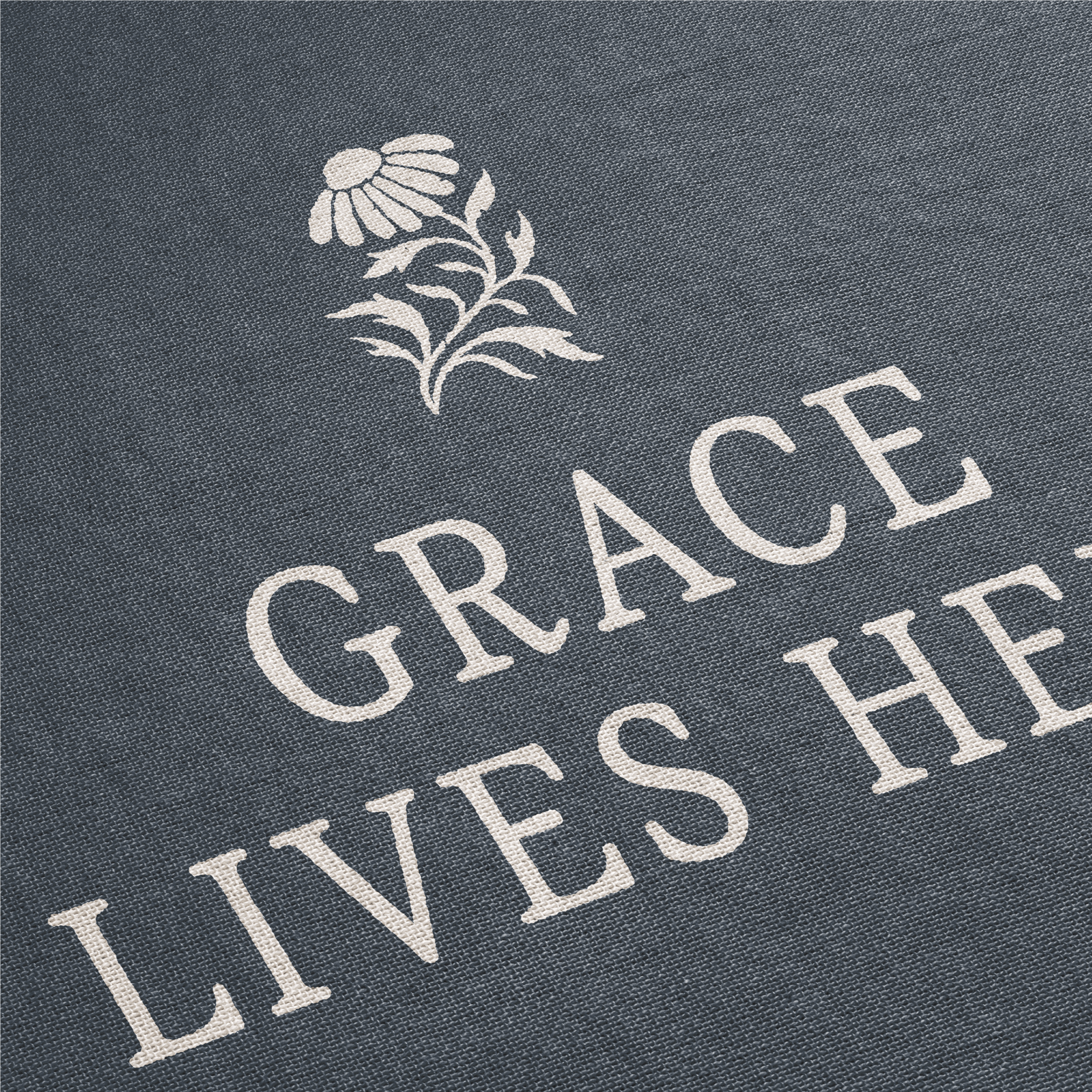Text 'GRACE LIVES HERE' with a floral design on a dark fabric background