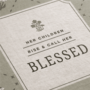 Textile with 'Her children rise and call her blessed' quote and floral design.